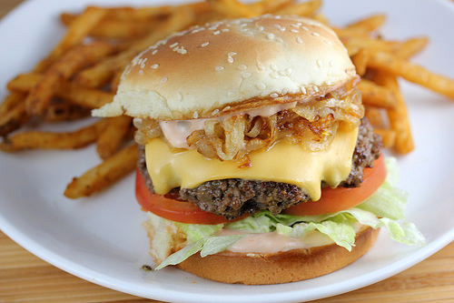 In N Out burger with lettuce tomato cheese and grilled onions served with fries