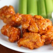 Spicy chicken bites served with celery and dipping sauce on a white plate