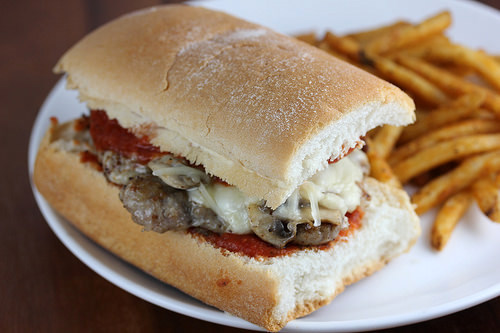 cudighi sausage sandwich with mozzarella, marinara sauce, mushrooms and onions on a toasted roll