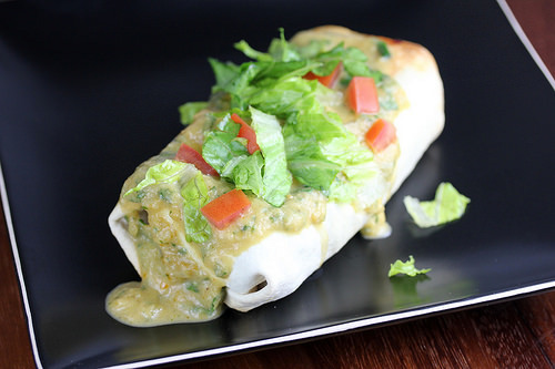 Chi Chis chimichanga topped with lettuce tomato and green sauce