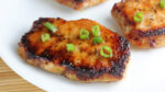 Prepared baked pork chops on white plate.