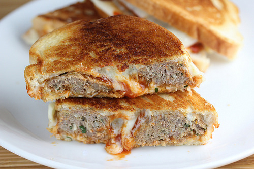 Meatball grilled cheese sandwich cut in half on a white plate
