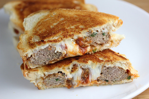 Meatball grilled cheese sandwich cut in half on a white plate