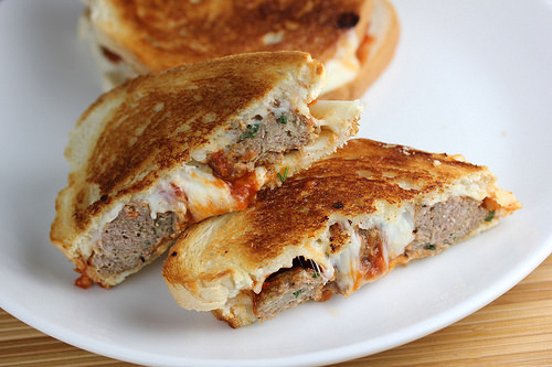 Meatball grilled cheese sandwich cut in half on a white plate