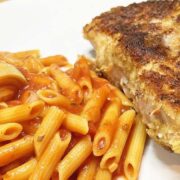 Prepared Parmesan pork chops on plate with pasta.