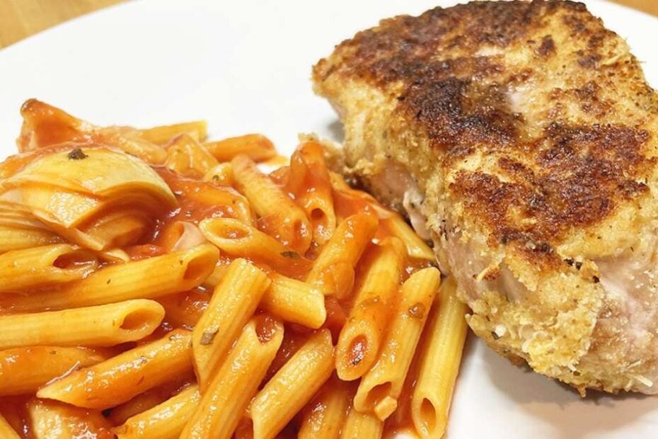 Prepared Parmesan pork chops on plate with pasta.