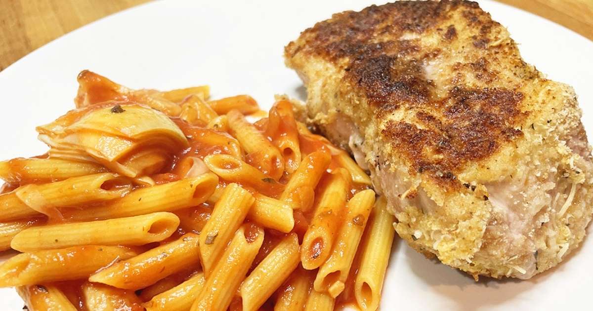 Prepared Parmesan pork chops on plate with pasta.