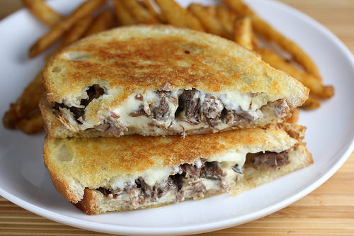 Short rib grilled cheese sandwich with melted cheese served with fries