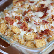 Tater tot casserole with melted cheese and crumbled bacon in a glass baking dish