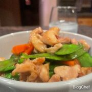 Chinese chicken with snow peas, served in a white bowl.