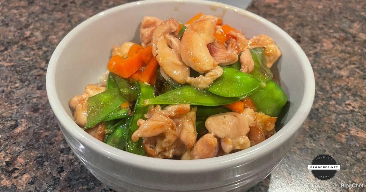 Chinese chicken with snow peas, served in a white bowl.