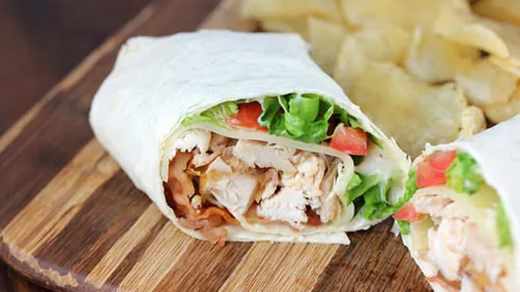 Chicken club wrap on a cutting board.