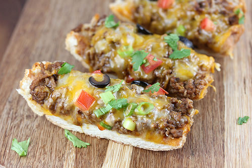 Slices of taco French bread pizza on a wooden board