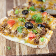 Slices of taco French bread pizza on a wooden board