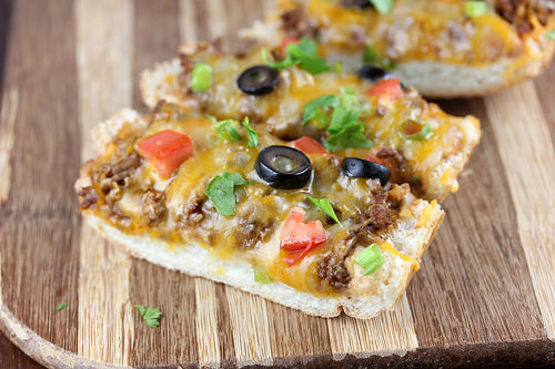 Slices of taco French bread pizza on a wooden board