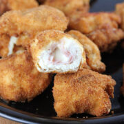 Plate of crispy cordon bleu chicken nuggets with melted cheese and ham filling.