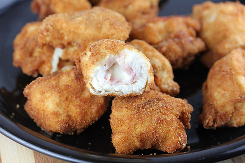 Plate of crispy cordon bleu chicken nuggets with melted cheese and ham filling.