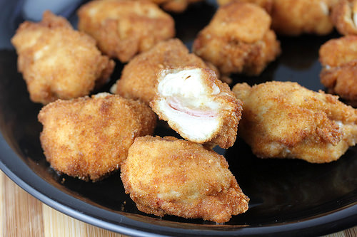 Plate of crispy cordon bleu chicken nuggets with melted cheese and ham filling.