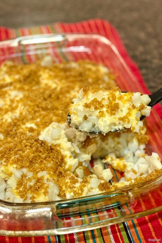 Prepared crunchy potato casserole with serving spoon