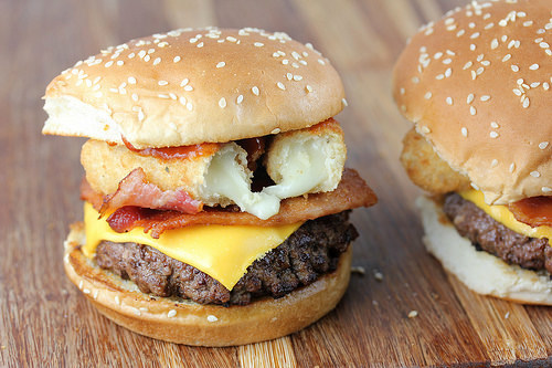 Mozzarella stick cheeseburger with bacon and beef patty on wooden surface