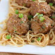 Juicy Asian pork meatballs garnished with green onions over noodles
