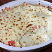 Cheesy crab casserole with golden brown topping in a round baking dish