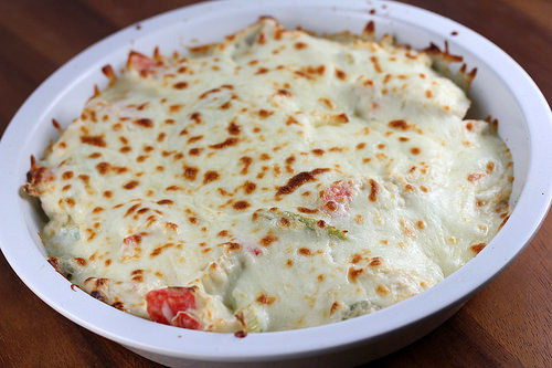 Cheesy crab casserole with golden brown topping in a round baking dish