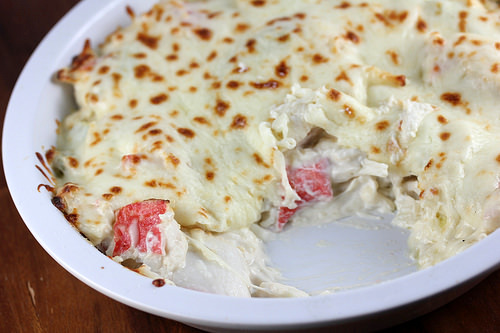Cheesy crab casserole with golden brown topping in a round baking dish