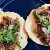 Prepared slow cooker barbacoa tacos on plate.