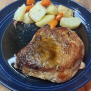 Prepared balsamic pork chop on plate with roasted vegetables.