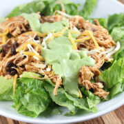 Chicken and black bean taco salad in a white bowl with lettuce and cheese
