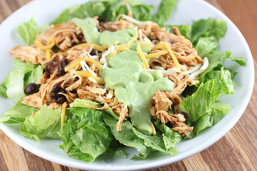Chicken and black bean taco salad in a white bowl with lettuce and cheese