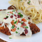 Chicken lombardy topped with melted cheese and mushrooms served with pasta.