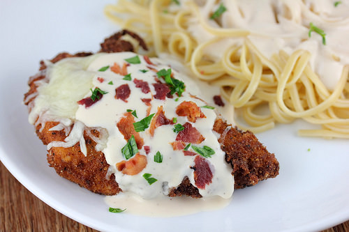 Chicken lombardy topped with melted cheese and mushrooms served with pasta.