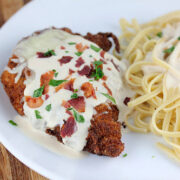 Chicken lombardy topped with melted cheese and mushrooms served with pasta.