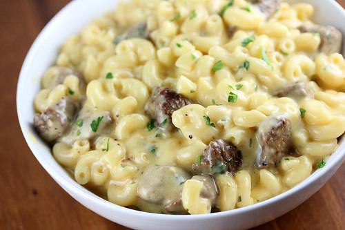 Bowl of steak mac and cheese topped with parsley