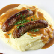 Plate of bangers and mash with brown gravy and parsley garnish