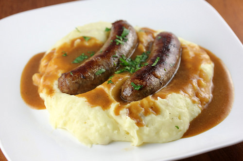 Plate of bangers and mash with brown gravy and parsley garnish
