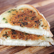 Toasted garlic bread grilled cheese on a wooden board with gooey cheese filling