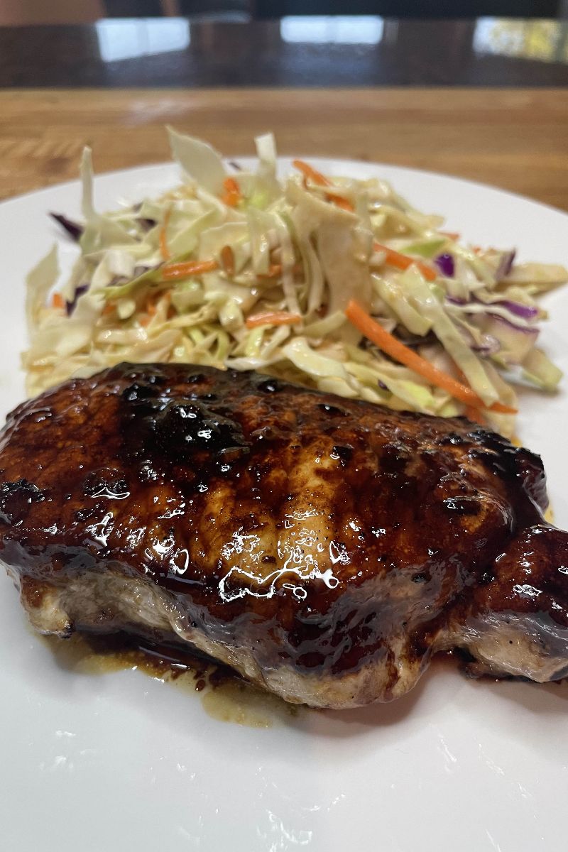 Prepared Korean style pork chops on plate with Asian slaw.