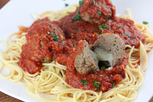 Plate of spaghetti topped with marinara sauce and asiago stuffed meatballs