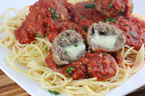 Plate of spaghetti topped with marinara sauce and asiago stuffed meatballs