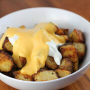 Cheesy fiesta potatoes topped with nacho cheese and sour cream in a white bowl
