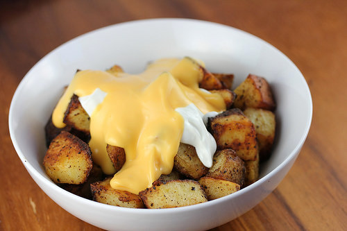 Cheesy fiesta potatoes topped with nacho cheese and sour cream in a white bowl