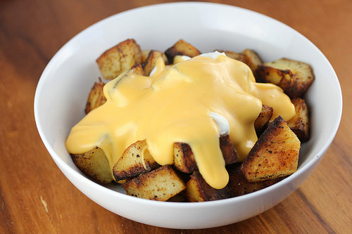 Cheesy fiesta potatoes topped with nacho cheese and sour cream in a white bowl