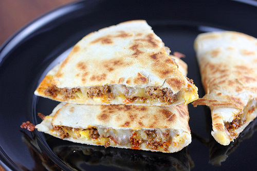Chorizo and egg quesadillas sliced and served on a black plate