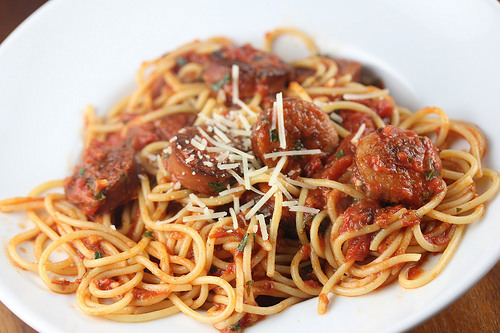 Spaghetti topped with smoked sausage marinara sauce and grated cheese