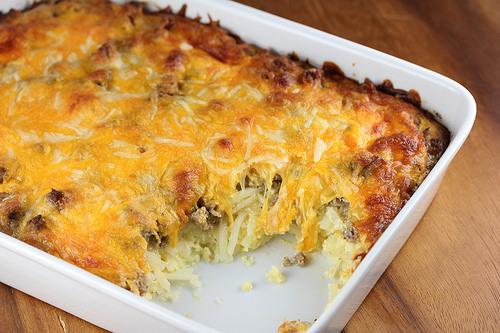 Cheesy sausage and hash brown casserole baked in a white dish