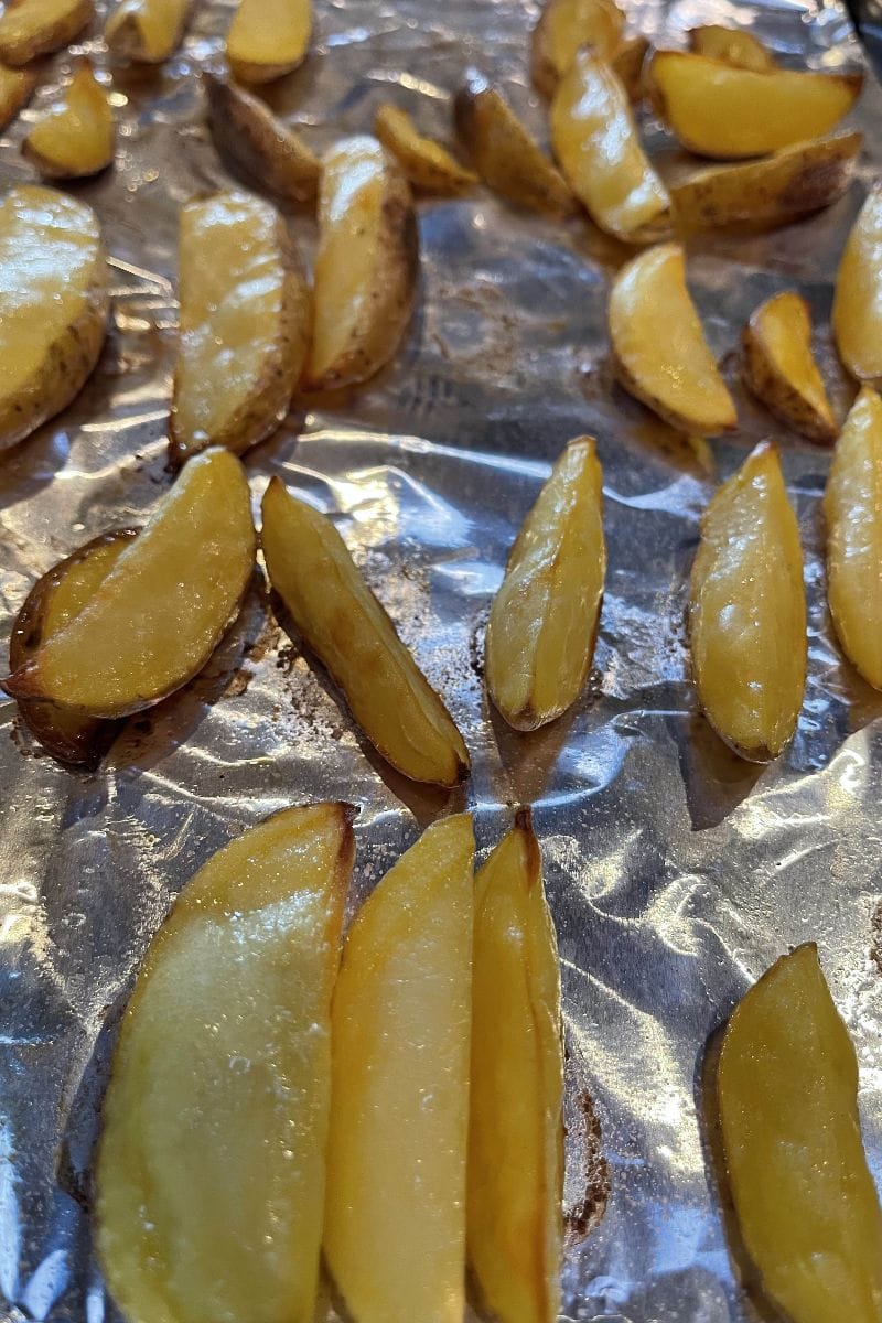Baked potato wedges on baking sheet.