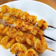 kewers of teriyaki grilled shrimp served on a white plat